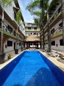 een zwembad op de binnenplaats van een hotel met palmbomen bij Hotel Kupuri in Sayulita