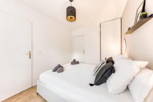 een witte slaapkamer met een groot wit bed met kussens bij Appartement 39m2 - Free Parking - Rer C - Métro 13-14 - Ascenseur - Easy Check in - in Asnières-sur-Seine