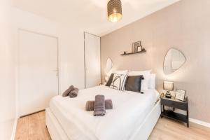 een slaapkamer met een groot wit bed met handdoeken erop bij Appartement 39m2 - Free Parking - Rer C - Métro 13-14 - Ascenseur - Easy Check in - in Asnières-sur-Seine +38 foto's