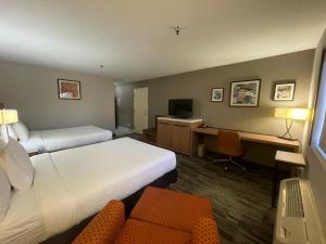 a hotel room with two beds and a desk with a computer at Grewal Hotel in Modesto