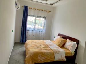 a bedroom with a bed with a window and a bedspread at Résidence Prestige KGV Appt 303 in Douala