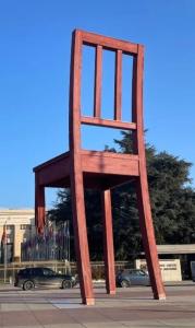 ein großer Holzstuhl, der mitten auf einer Straße steht in der Unterkunft Quarto lux Centro Geneve 5 estrela in Arni Alp