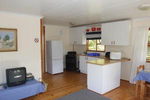uma cozinha com armários brancos e uma televisão em Nibelheim Self Catering Cottage em Hogsback