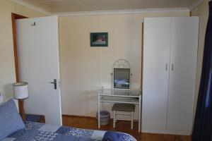 1 dormitorio con escritorio, 1 cama y espejo en Nibelheim Self Catering Cottage, en Hogsback