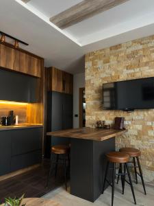 a kitchen with a bar with stools and a tv at Mountain Hearth - Milmari Resort in Kopaonik