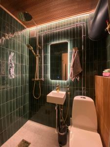 a green tiled bathroom with a toilet and a sink at Atelier Torppa in Rovaniemi