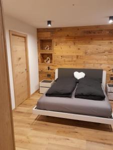 a bedroom with a bed with a wooden wall at Casa Zena in Tesero