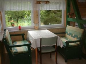 a dining room with a table and chairs and two windows at Holiday Home mit Bergblick by Interhome in Ilfeld