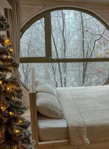 BarajevoFuro Treehouse的一间卧室，带窗户，里面有一张床和一棵圣诞树