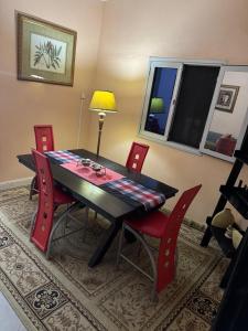 un tavolo da pranzo con sedie rosse, un tavolo e una lampada di Ô bien être a Saint-Louis