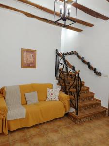 een woonkamer met een gele bank en een trap bij Señorío de Ves in Casas de Ves