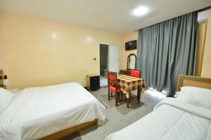 Una habitación de hotel con dos camas y una mesa y sillas. en HOTEL VELLEDA, en Rabat