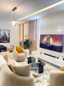ein Wohnzimmer mit einem großen Fernseher und einem Sofa in der Unterkunft 2-Bedroom Apartment with Pool, Gym, Snooker & Table Tennis in Lekki Ajah in Lekki
