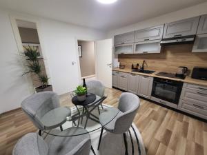 a kitchen with gray chairs and a table in a kitchen at KRUNA Apartment in Cazin