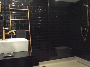 a black tiled bathroom with a sink and a tub at Apartment Kleines Loft by Interhome in Gais