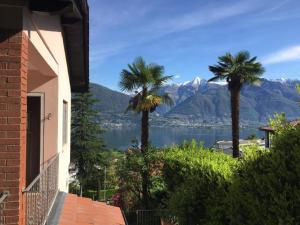 a house with palm trees and a view of the water at Apartment Casa Barbara by Interhome in Piazzogna