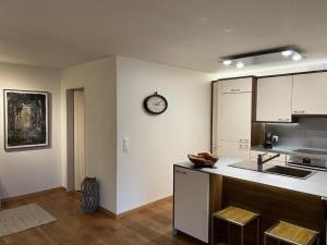 a kitchen with white cabinets and a clock on the wall at Apartment Chäserruggblick by Interhome in Unterwasser