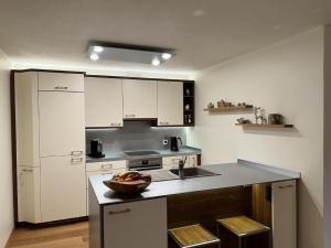 a kitchen with white cabinets and a bowl of fruit on a counter at Apartment Chäserruggblick by Interhome in Unterwasser +35 photos