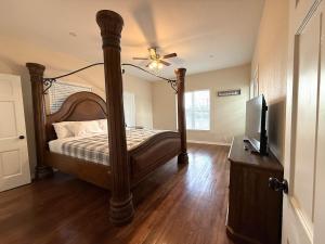 een slaapkamer met een hemelbed en een televisie bij River Side Private Retreat in Seguin