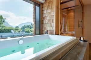 a large tub in a bathroom with a large window at Klosterhof – Alpine Hideaway & Spa in Bad Reichenhall