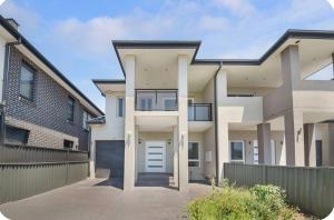 a large white house with a fence and a garage at Lovely Duplex in Cabramatta West 4 bedrooms in Cabramatta Station