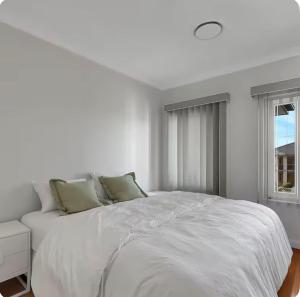 a white bedroom with a white bed and a window at Lovely Duplex in Cabramatta West 4 bedrooms in Cabramatta Station