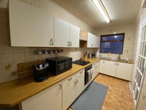 eine Küche mit weißen Schränken und einer Mikrowelle in der Unterkunft Bungalow in Badsey, north of Cotswolds in South Littleton