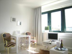 a white room with a desk with a computer and chairs at A-Partments in Cologne