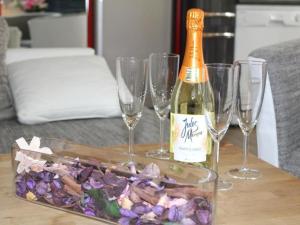 a bottle of champagne and four wine glasses on a table at Apartment Vulkaneifel by Interhome in Daun