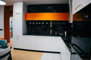 een keuken met witte kasten en een oranje en zwarte muur bij Amarus Apartments in Gjirokastër +32 foto's