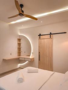 a bedroom with a ceiling fan and a door at Cocomero Inn in Fulidhoo