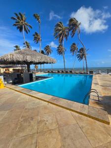 a swimming pool with palm trees and the ocean at Eco Paradise 129 in Caucaia