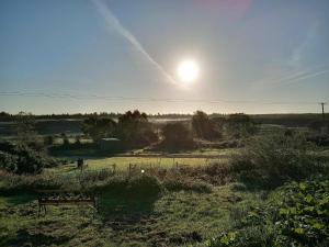een bank in een veld met de zon in de lucht bij Stag's View in Ballina