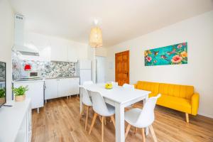 eine Küche und ein Esszimmer mit einem weißen Tisch und einem gelben Sofa in der Unterkunft Gran Sol Family 5 in Cala Ferrera