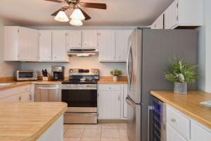 a kitchen with white cabinets and a stainless steel refrigerator at Minutes to Private Association in Eastham +32 photos