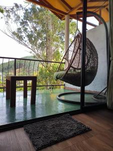 een veranda met een schommel, een tafel en een raam bij Slon White Elephant Ella in Ella