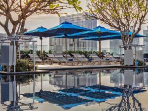 a swimming pool with blue umbrellas and chairs at Mercure Bangkok Sukhumvit 24 in Bangkok
