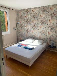 Schlafzimmer mit einem Bett mit weißer Bettwäsche und Blumentapete in der Unterkunft Au pied des quais avec balcon in Auxerre