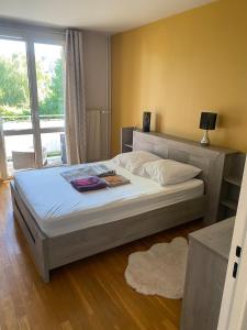 ein großes Bett in einem Schlafzimmer mit großem Fenster in der Unterkunft Au pied des quais avec balcon in Auxerre