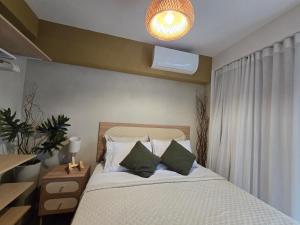 a bedroom with a bed with white sheets and green pillows at Conforto e Lazer a 50m da Praia in Niterói +15 photos
