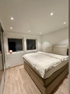 a bedroom with a large bed and two windows at Nordic Panorama in Tromsø