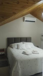 un lit blanc dans une chambre avec un plafond en bois dans l'établissement Ametista Apartment, à Nova Petrópolis