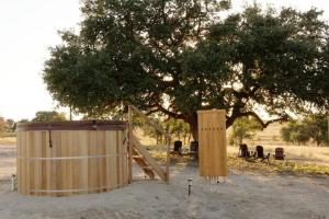 a wooden fence and a tree with chairs under it at Johnny Yurts in Johnson City