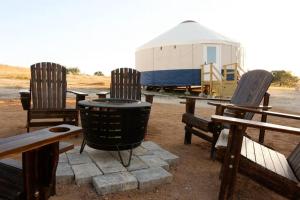 een groep banken en een vuurkuil met een gebouw bij Johnny Yurts in Johnson City