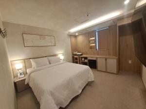 a bedroom with a large white bed and a window at 그랑메종 바오밥 호텔 in Gwangju