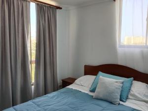 een slaapkamer met een bed met blauwe en witte kussens bij Departamento 2D 1B 1E in La Serena