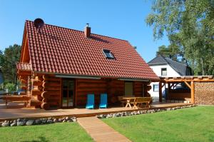 a log cabin with a deck and a patio at Naturstamm Ferienhaus in Trassenheide