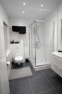 a white bathroom with a shower and a toilet at Durdi Hotels - Serviced Apartments - 24h Self-Check-in & Parking in Groß-Zimmern