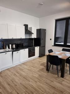 eine Küche mit weißen Schränken und einem Holztisch mit einem Esszimmer in der Unterkunft Apartament z tarasem in Kutno + 3 Fotos