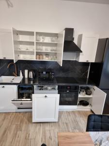 eine Küche mit weißen Schränken und schwarzen Geräten in der Unterkunft Apartament z tarasem in Kutno